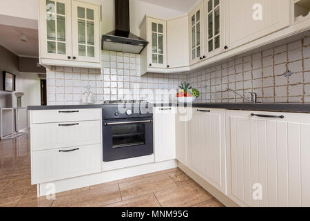 Small functional kitchen interior with stylish furniture and modern tiling Stock Photo