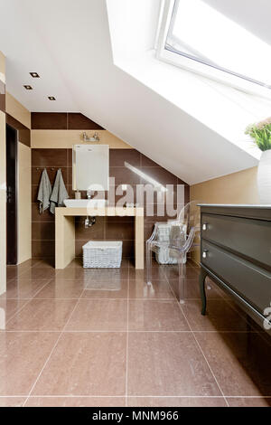 New style attic bathroom with brown tiling, mirror and countertop basin Stock Photo