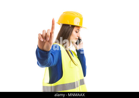 Young woman architect or engineer making hold gesture with index finger and using smartphone as important business call concept isolated on white back Stock Photo