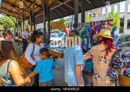 ASHEVILLE, NC, USA-13 MAY 18: Shoppers gathered at a craft display, looking at colorful tie-dyed T-shirts.
