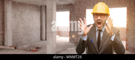 Senior architect or engineer stressful keeping hands on head, terrified in panic, shouting at unfinished building Stock Photo