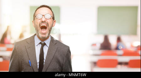 Teacher man using glasses stressful, terrified in panic, shouting exasperated and frustrated. Unpleasant gesture. Annoying work drives me crazy at cla Stock Photo