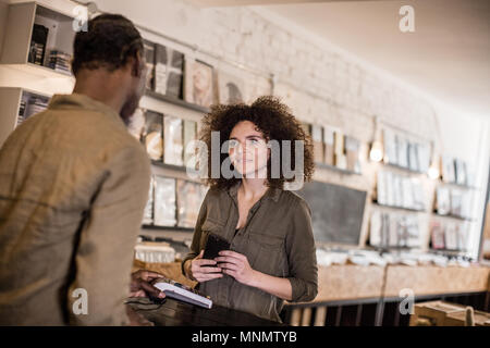 Customer making payment with smartphone in a record store Stock Photo