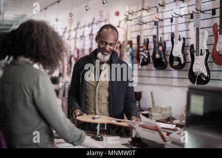 Senior male buying an acoustic guitar Stock Photo