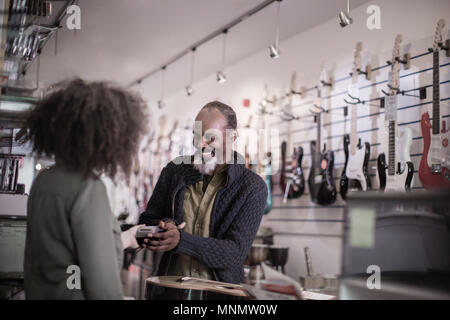 Senior male paying in a guitar store with credit card Stock Photo