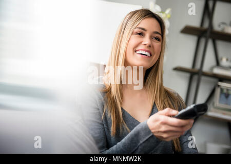 Young woman watching tv and laughing Stock Photo