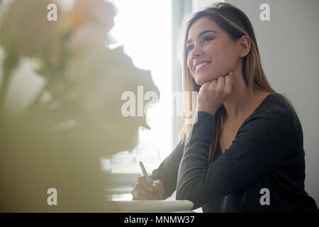 Smiling young woman sitting at desk Stock Photo