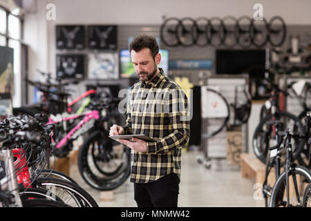 Small business owner using digital tablet in a cycle store Stock Photo
