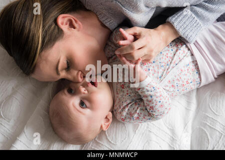 Mother kissing baby girl (18-23 months) with care Stock Photo