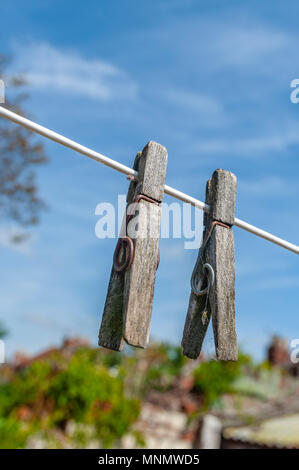 Old wooden clothes pegs on a clothes line on a summer afternoon against a clear blue sky Stock Photo