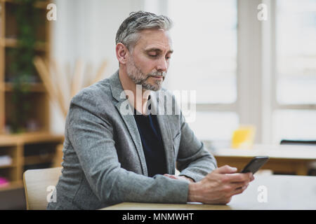 Businessman using smartphone at desk Stock Photo