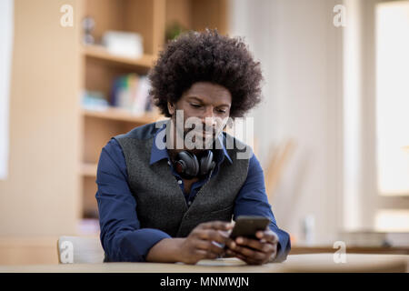 Businessman using smartphone at desk Stock Photo