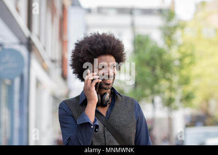 African American male walking and on on smartphone in city Stock Photo
