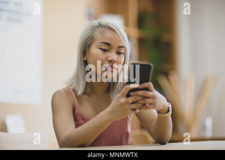 Young adult female using smartphone in college Stock Photo