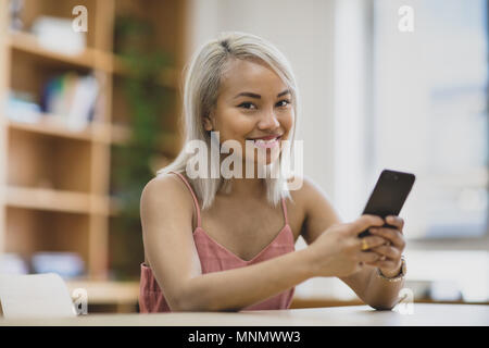 Young adult female using smartphone in college Stock Photo