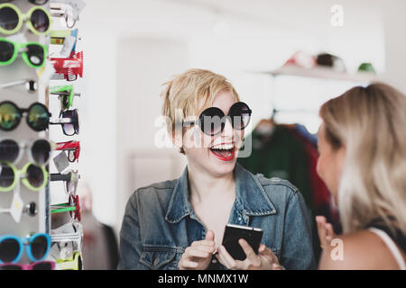 Millennials trying on sunglasses in a vintage store Stock Photo