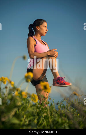 Woman stretching against blue sky Stock Photo