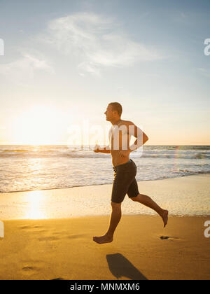 Man jogging along beach Stock Photo