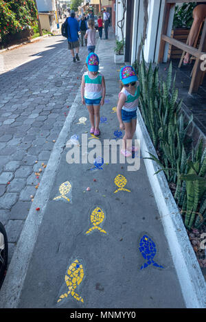 Kids playing on a sidewalk with tile fish in g Stock Photo