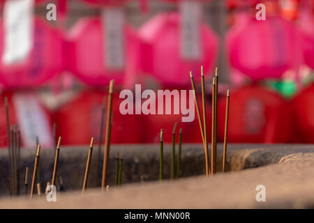 Incense sticks in front of red lanterns hanging in rows at a Buddhist Temple in Seoul, South Korea at the Lotus Lantern Festival in celebration of Bud Stock Photo