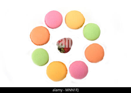 Multicolored macaroons around the strawberry isolated on white background Stock Photo