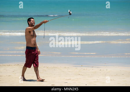 Man taking a picture of himself using a selfie stick, Santa Cruz Island, Galapagos Islands, Ecuador. Stock Photo