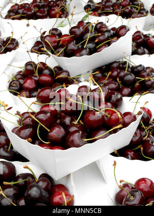 Closeup of fresh red cherries in white paper baskets at the Cours Saleya Market in Nice, France Stock Photo