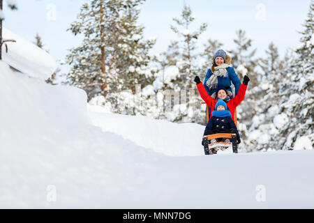 Beautiful family of mother and kids enjoying snowy winter day outdoors having fun sledging Stock Photo