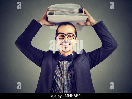 Happy businessman with office binders standing smiling at the camera balancing them on head pleased with corporate busy life Stock Photo