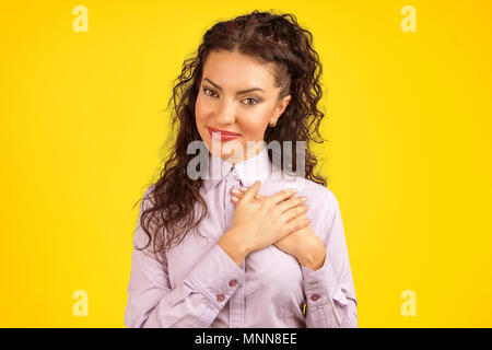 Faithful woman keeps hands on chest near heart, shows her kindness, expresses sincere emotions, being kind hearted Stock Photo