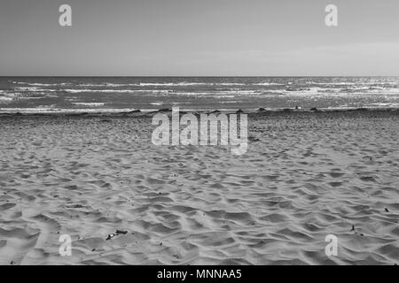 Sandy beach with seaweed and sand castle black and white effect, Bibione, Veneto, Italy Stock Photo