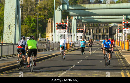 Joggers and cyclists crossing the Cardiff Bay barrage in early morning light Stock Photo