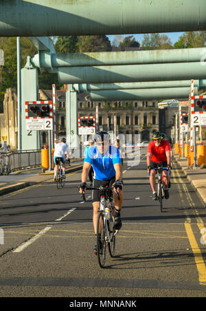 Joggers and cyclists crossing the Cardiff Bay barrage in early morning light Stock Photo