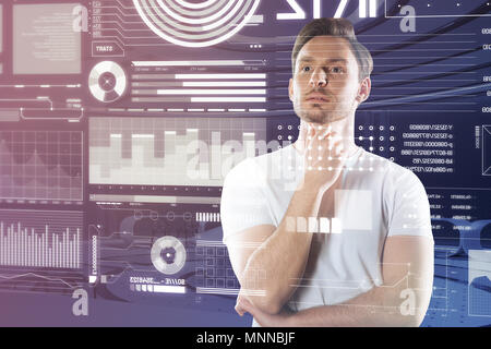Young man looking at the screen and thoughtfully touching his chin Stock Photo