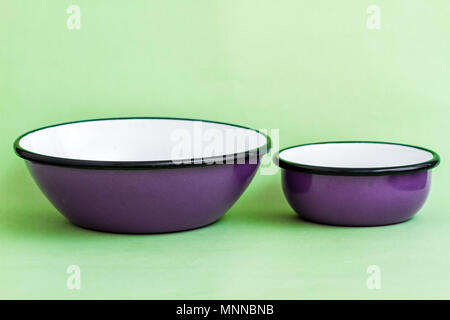 Purple enamel bowls on green background Stock Photo