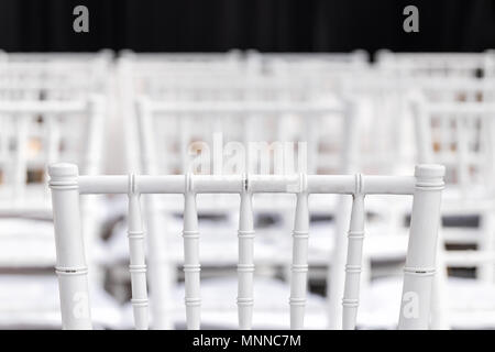 Closeup of one white wedding chair for ceremony with background of rows of many seats pattern bokeh, nobody Stock Photo