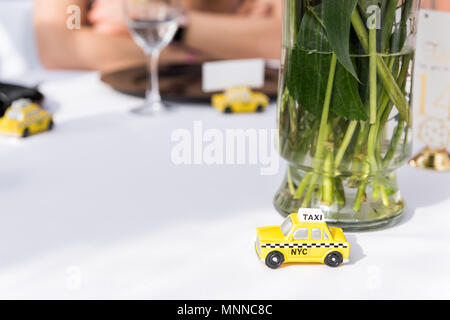 New York City, USA - April 7, 2018: NY NYC yellow taxi cab souvenir cute small toy car wedding favor gift decorations on reception table white cloth c Stock Photo