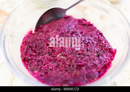 Macro closeup of traditional Russian or Ukrainian shredded boiled beet salad, shuba, with garlic, mayonnaise as appetizer, side dish on table with spo Stock Photo