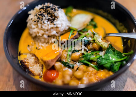 Closeup of Indian meal lunch or dinner dish in traditional Asian restaurant or cafe with vegetable sweet potato orange curry, sesame seeds, brown rice Stock Photo