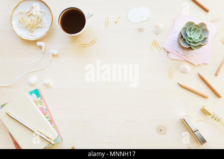 Female home office desk table in pastel tones. Workspace with notebooks, cup of coffe and decorations on light wooden background with copy-space. Flat Stock Photo