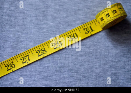 The Measuring Tape of Yellow Color with Numerical Indicators in the Form of  Centimeters or Inches Lies on a Gray Knitted Fabric. Stock Photo - Image of  sewing, ruler: 116542110