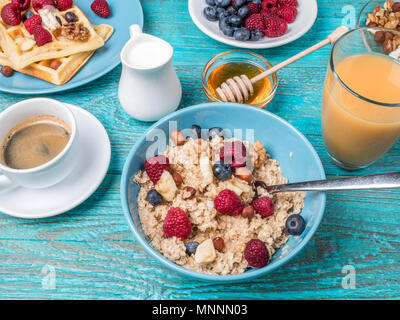 Bowl of oatmeal with raspberries and blueberries on a blue wooden table. Stock Photo