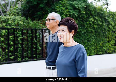 Senior Asian couple walking in the park of residential house Stock Photo