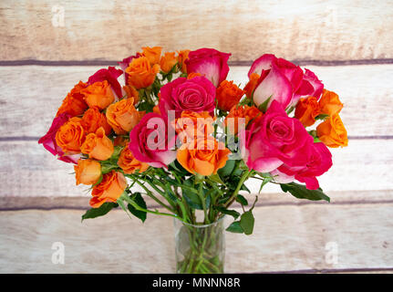 A beautiful and colorful bouquet of white with pink tips and orange roses on a wood grain backdrop. Stock Photo