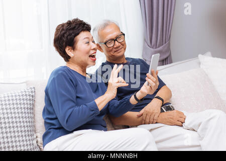 Senior Asian couple grandparents making a video call and waving at the caller Stock Photo