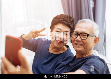 Senior Asian couple grandparents taking a selfie photo together at home Stock Photo