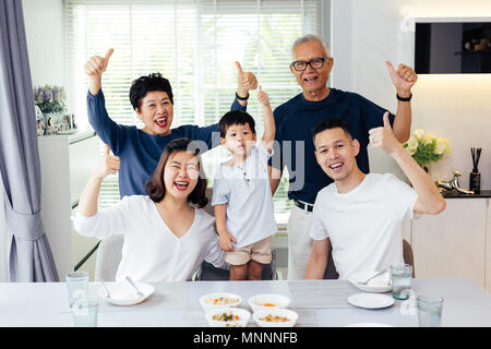 Extended Asian family of three generations having a meal together and showing thumbs up at home with happiness Stock Photo