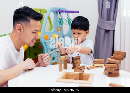 Asian child and father playing with wooden blocks in the room at home. A kind of educational toys for preschool and kindergarten kids