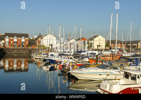 Yachts and motor boats berthed in Penarth Marina, Cardiff, Wales, in early morning light, with reflections in still water Stock Photo