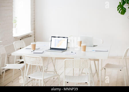 Meeting table with laptops and coffee in empty office room Stock Photo